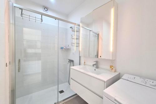 La salle de bains blanche est pourvue d'un lavabo et d'une douche. dans l'établissement V&V Amadores Apartment, à Puerto Rico