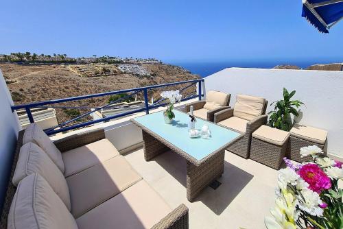 taras ze stołem i krzesłami i widokiem na ocean w obiekcie V&V Amadores Apartment w mieście Puerto Rico de Gran Canaria
