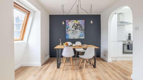 a dining room with a wooden table and white chairs at Cracking Central Loft Apartment, Old Town in Hastings