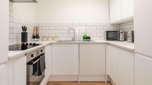 a white kitchen with a sink and a microwave at Cracking Central Loft Apartment, Old Town in Hastings