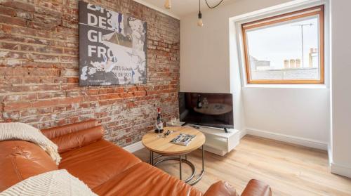 a living room with a couch and a brick wall at Cracking Central Loft Apartment, Old Town in Hastings