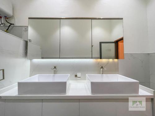 a bathroom with two white sinks and a mirror at Palisades Peaks Luxury Apartments in Lekki