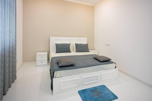 una camera da letto bianca con un letto grande con un tappeto blu di Clintonvilla 4-bedroom with pool near to Airport a Negombo
