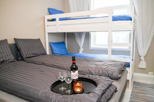 Zimmer mit 2 Etagenbetten, einem Tisch mit einer Flasche und Gläsern in der Unterkunft Moderne leilighet ved Solsiden i Trondheim in Trondheim