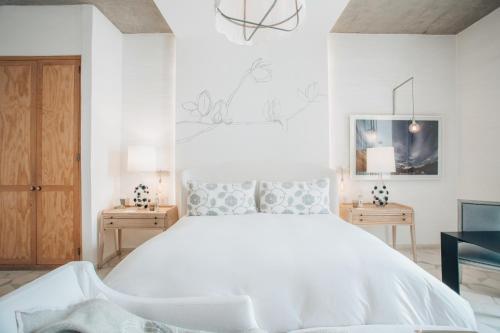 a white bedroom with a large bed and two night stands at LOtel-Casa Arca in San Miguel de Allende