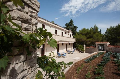 a stone building with tables and chairs in a yard at White house in the forest in Pučišća