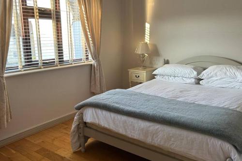 a bedroom with a bed with a blue blanket and a window at Cosy 2 bed, home from home in Haddenham