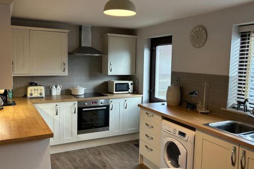 a kitchen with white cabinets and a stove top oven at Cosy 2 bed, home from home in Haddenham