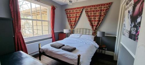 een slaapkamer met een bed met rode gordijnen en een raam bij The Tuck Away, Central Old Town with Parking in Hastings