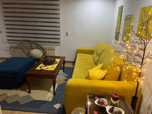 a living room with a yellow couch and a table at Apartman SI in Banja Luka