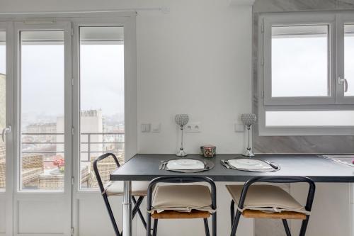 uma cozinha com mesa, cadeiras e janelas em Les Bleus de Paris studio flat em Gentilly