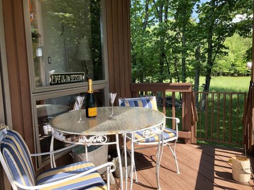 a table and chairs on a porch with a bottle of wine at Mountain Condo with Modern Cabin Style in East Jewett