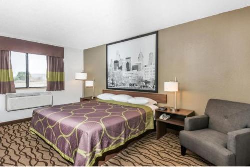 a hotel room with a bed and a chair at Super 8 by Wyndham Bedford in Bedford