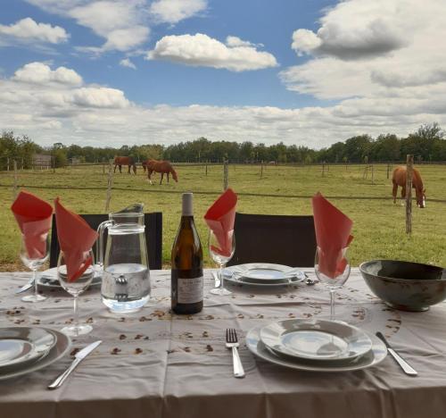 a table with a bottle of wine and plates and glasses at Domaine du Boscq in Parleboscq