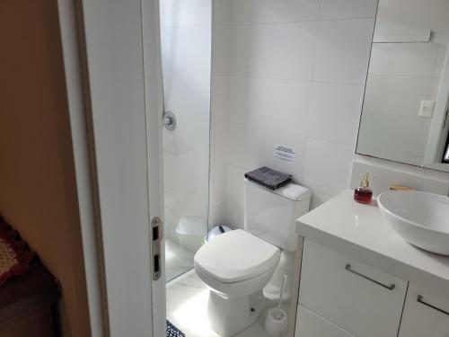 Baño blanco con aseo y lavamanos en Apartamento Florianópolis Canasvieiras, en Florianópolis