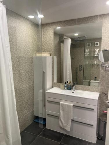 bagno con lavandino e doccia con specchio di 2 Bedroom Chelsea Apartment a Londra