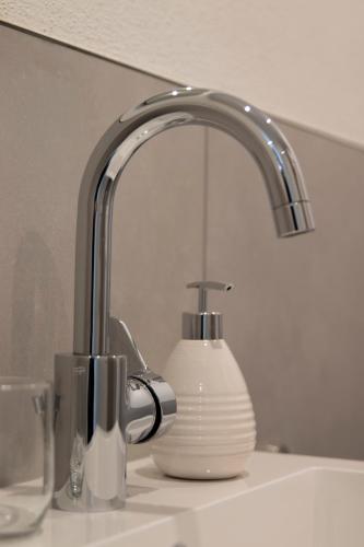 a sink with a faucet and a white soap dispenser at Apartment Alte Raiffeisenkasse Rothenburg ob der Tauber in Rothenburg ob der Tauber