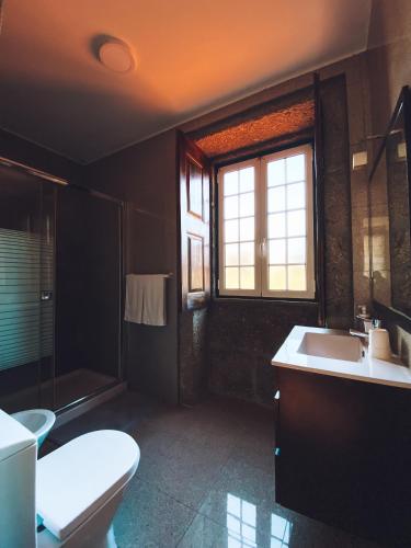 a bathroom with a toilet and a sink and a window at Casa da Tanquinha in Beiral do Lima