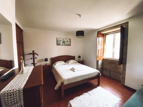 a bedroom with a bed and a cross on a dresser at Casa da Tanquinha in Beiral do Lima
