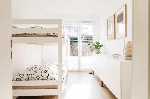 a white room with bunk beds and a desk at Ferienwohnung Nordic Calm am Kellersee in Malente