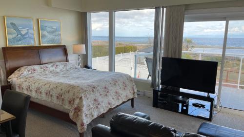a bedroom with a bed and a flat screen tv at Buena Vista by the Sea in Qualicum Beach