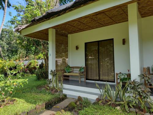 Una casa con un porche con un banco. en Happy Coconut Camiguin en Mambajao