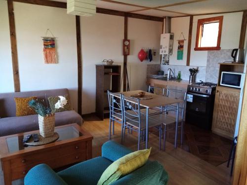 sala de estar con sofá, mesa y cocina en Cabañas Rincón de Ten Ten, en Castro