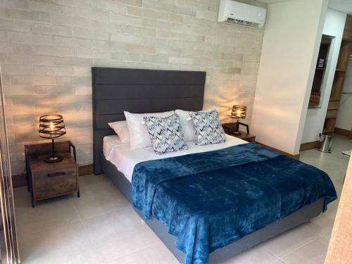 een slaapkamer met een groot bed en een blauwe deken bij Apartamento en Granada con piscina, turco, estacionamiento in Cali