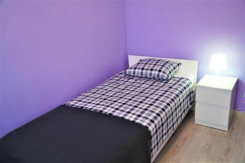 ein lila Schlafzimmer mit einem Bett und einem Nachttisch in der Unterkunft Jedenastka in Płock