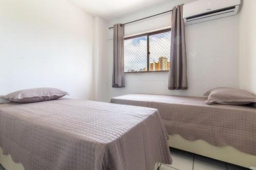 a bedroom with two beds and a window at Residencial Califórnia em Lagoa Nova por Carpediem in Natal