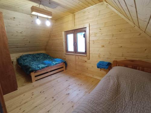 a room with a bed and a window in a log cabin at Domek w Świątkowej in Krempna