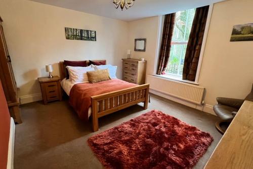 a bedroom with a bed with a red blanket and a red rug at Pavilion View in Buxton