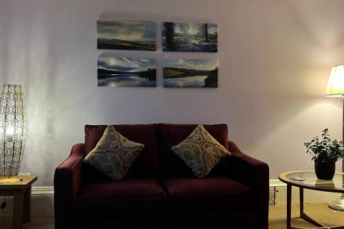 a couch in a living room with three paintings on the wall at Pavilion View in Buxton