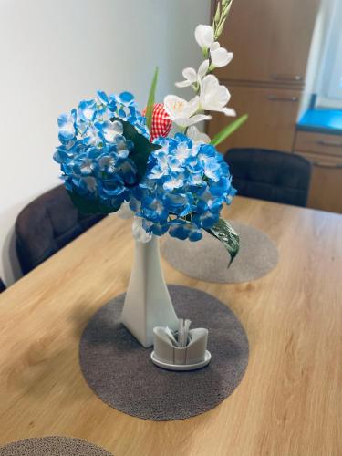 a white vase with blue and white flowers on a table at RELAX APPARTEMENT - Graz in Graz