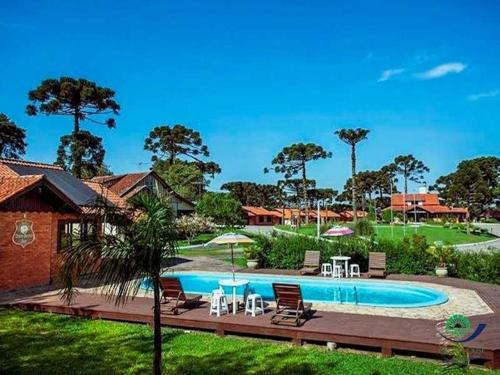 a pool with chairs and tables in a yard at Morada Das Araucárias in São Francisco de Paula
