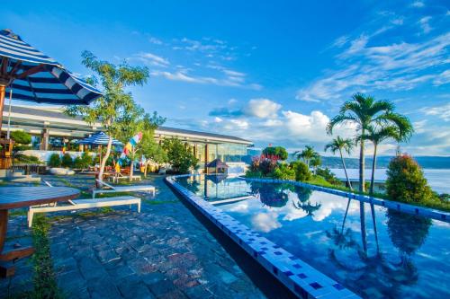 a resort swimming pool with a view of the ocean at Estrella Hotel & Conference in Luwuk