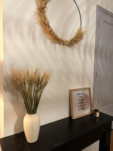 a vase on a table with a picture and a wreath at Appart chaleureux face gare in Limoges