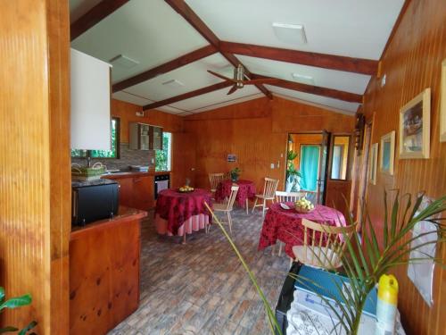 a living room with two tables and a kitchen at Hostal Makohe Rapa Nui in Hanga Roa