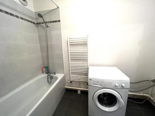 a bathroom with a washing machine next to a bath tub at Paris La-Defense - U Arena - 2 Bedrooms - Parking, Terrace & Wifi in Nanterre