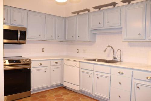 a white kitchen with white cabinets and a sink at 2 BDR with Workspace & Patio in Montrose in Houston