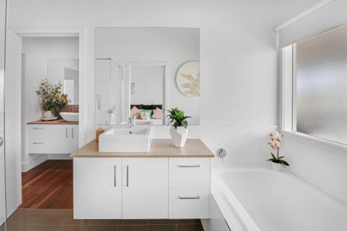 ein weißes Badezimmer mit einem Waschbecken und einem Spiegel in der Unterkunft Loyola Lake House in Mansfield