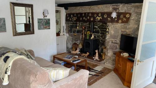 a living room with a stone fireplace and a couch at Cosy Nook in North Molton