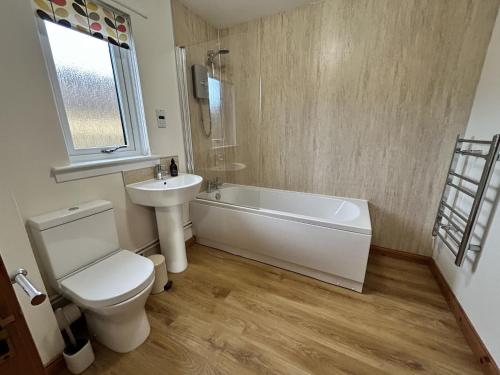 a bathroom with a toilet and a tub and a sink at Fern Cottage in Lairg