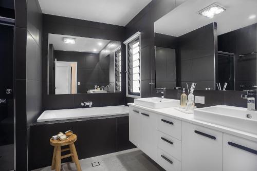 a black and white bathroom with two sinks and a mirror at Executive, modern waterfront house in Maroochydore