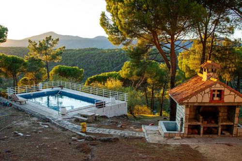 una piscina con una pequeña casa al lado en Casa Cadalso, Mirador de Gredos, Madrid, en Cadalso de los Vidrios