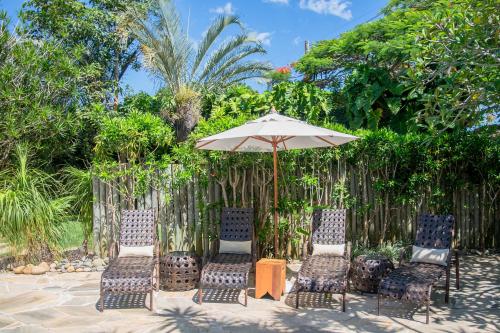 a group of chairs and an umbrella in front of a fence at Pousada da Cyssa in Búzios