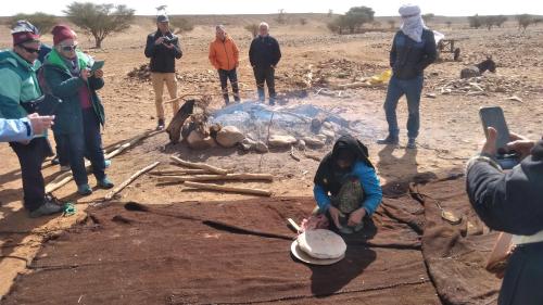 a group of people standing around a fire at Erg Chigaga Regency Camp in El Gouera