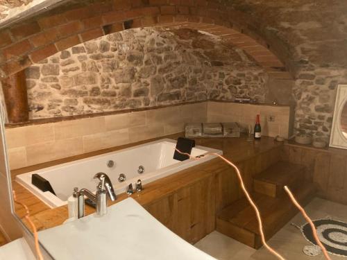 Una bañera en una cocina con pared de piedra. en Suíte Sant Sebastià con jacuzzi, sauna y jardín, en Moià