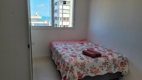 1 dormitorio pequeño con 1 cama con manta de flores en Praia Grande (13) - 2 quartos - 1 quadra Mar, en Torres