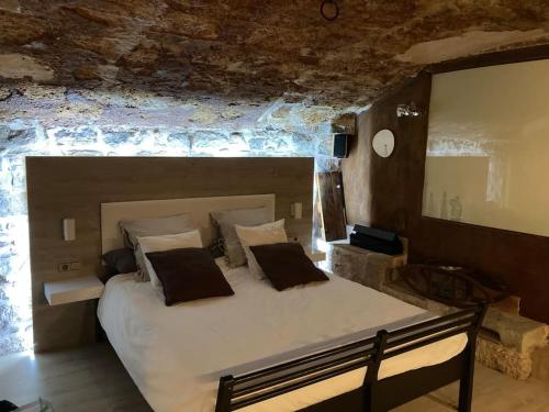 1 dormitorio con 1 cama grande en una pared de ladrillo en Suíte Sant Sebastià con jacuzzi, sauna y jardín, en Moià